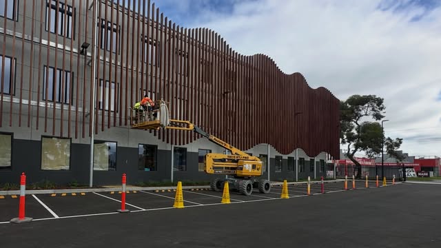 Commercial facade with vertical battens and elevated access equipment